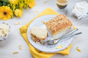 a loaf of coffee cake on a plate with flowers and slices of banana