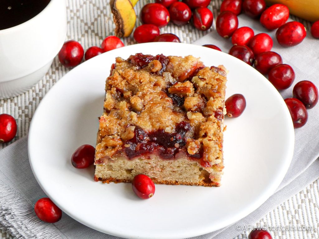 a slice of coffee cake on a white place with cranberries