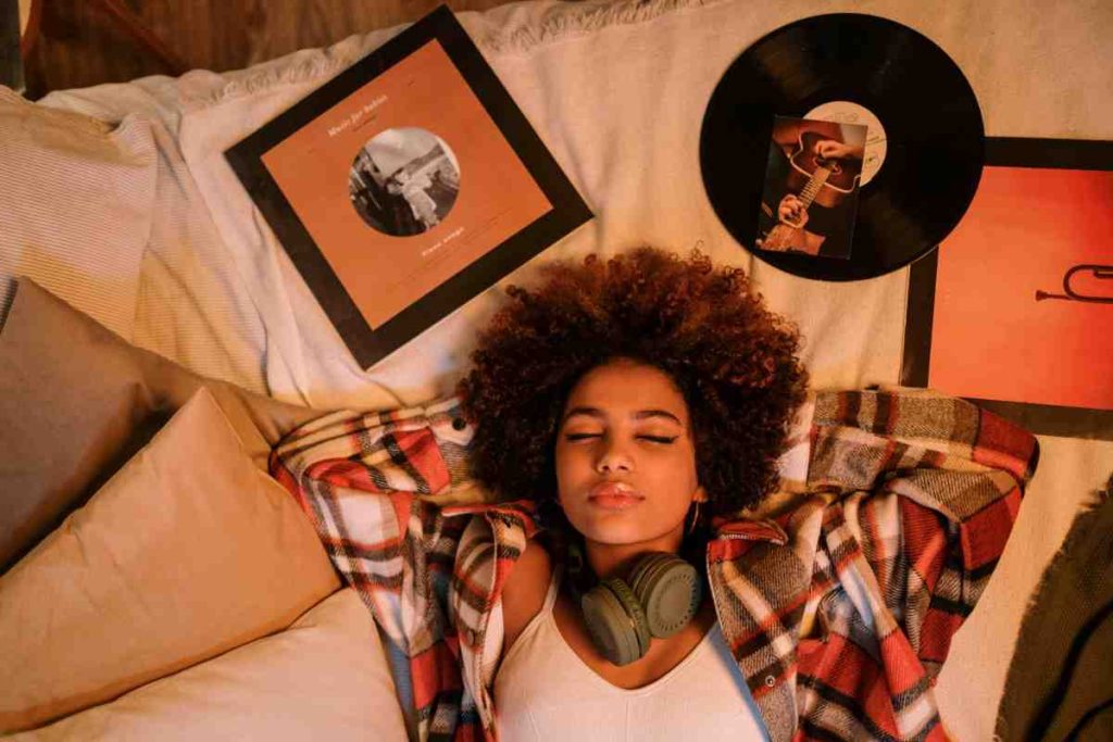 woman listing to music with albums beside her