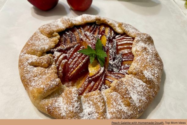 A pie with fruit on top and a leaf sprinkled with powdered sugar