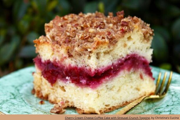 a square cut of cherry coffee cake with a red ribbon of cherries in the middle and crumble topping