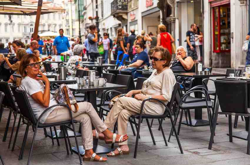 people sitting at an outdoor cafe in Trieste drinking coffee