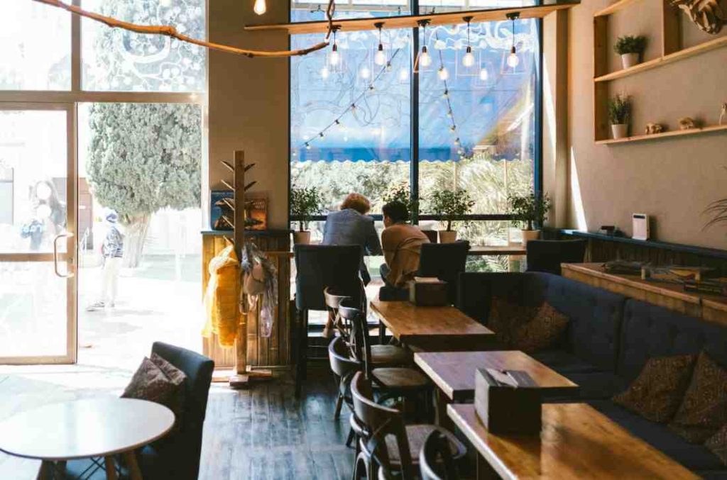 two people sitting in a coffee bar with a street view